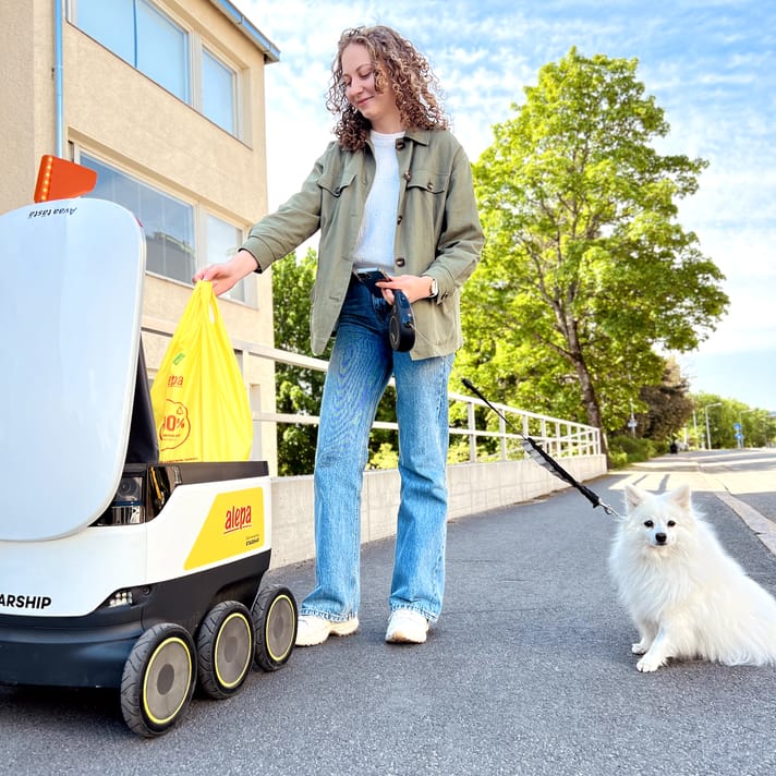 Person picking up their S-kaupat grocery order from an opened Starship robot